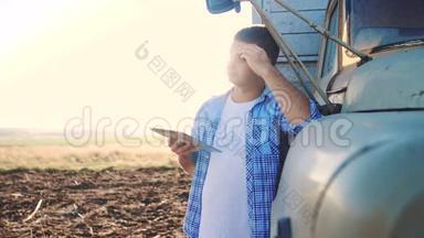 智慧农业。 男子农民司机站在卡车附近的数字生活方式平板电脑。 慢动作视频。 肖像